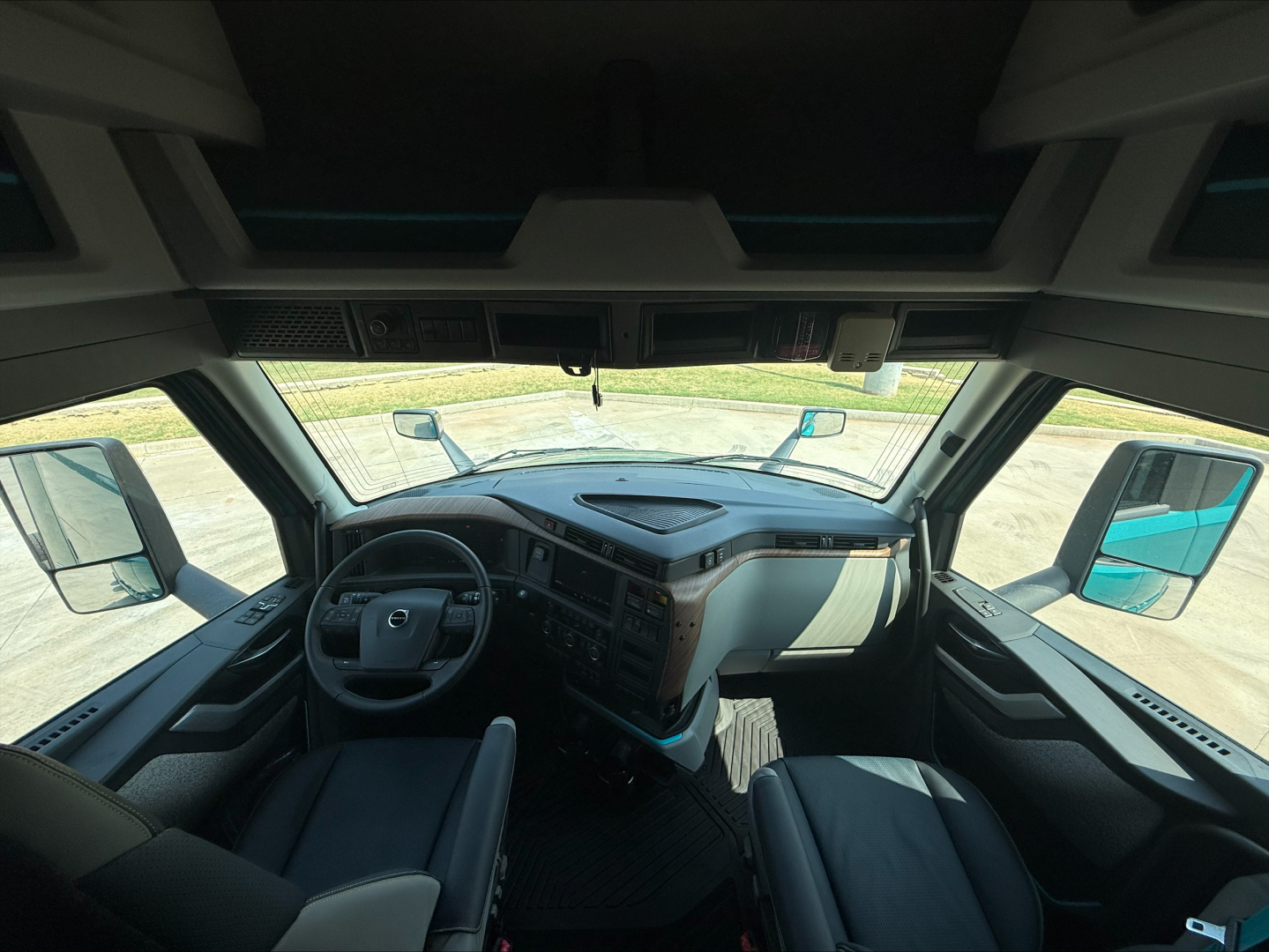 Interior view of a 2027 Volvo VNL64T860 truck cab showing dashboard, steering wheel, and driver seat from a forward angle.