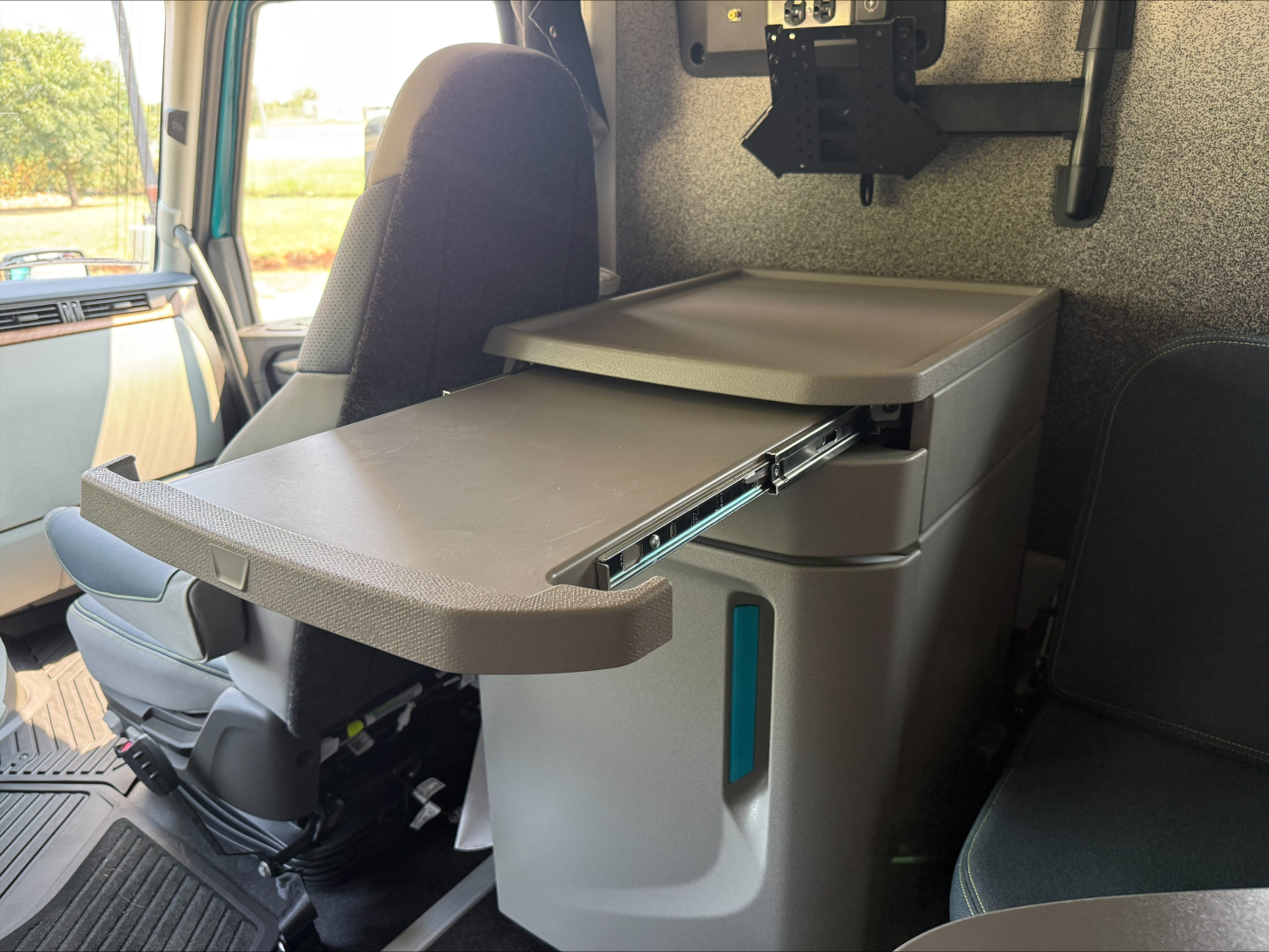 Truck cab interior showing a fold-out armrest/curved tray attached to a center console in a Volvo VNL64T860 sleeper cab.