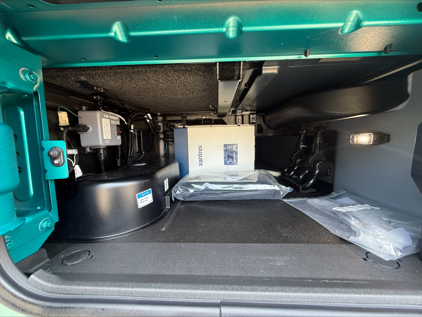 Volvo VNL64T860 truck interior storage compartment with cabinets, boxes, and plastic-wrapped items visible in cargo area.