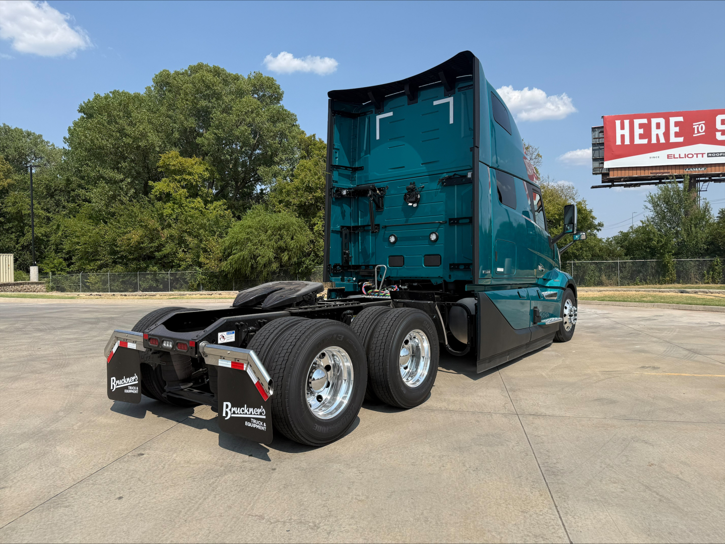 Volvo VNL64T860 cab-over truck rear view showing dual rear axles and fifth-wheel with mud flaps and side mirrors.