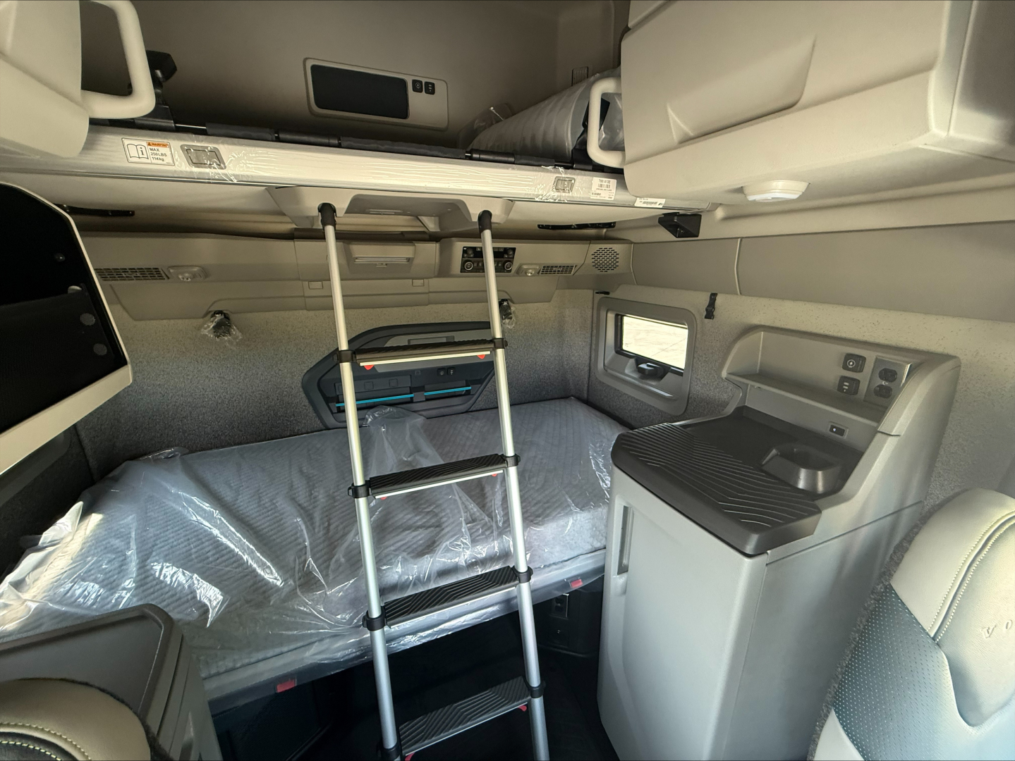 Volvo VNL64T860 sleeper cab interior showing bunk area with ladder, overhead storage, and side control panel.