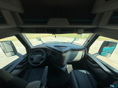 Interior view of a 2027 Volvo VNL64T860 truck cab showing dashboard, steering wheel, and driver seat from a forward angle.