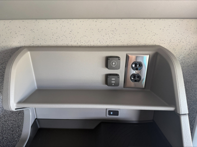 Truck cab interior showing power outlets and a USB-C/2x 120V socket panel in the dash area with a small storage shelf.