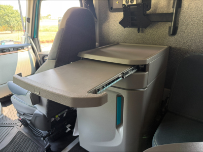 Truck cab interior showing a fold-out armrest/curved tray attached to a center console in a Volvo VNL64T860 sleeper cab.