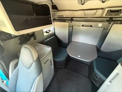 Interior view of a Volvo VNL64T860 sleeper cab showing table in cabin with seating and storage compartments.