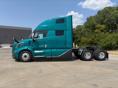 Volvo VNL64T860 sleeper cab truck side view showing turquoise body, large aerodynamic hood, dual rear axles, and chrome wheels.