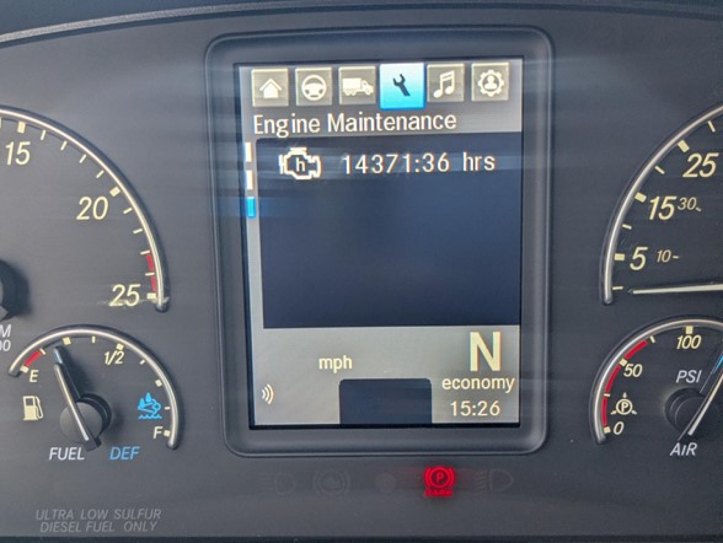 Truck instrument cluster display showing Engine Maintenance icon and 14371:36 hrs while gear indicator shows N for neutral; speed/eco gauges on sides.
