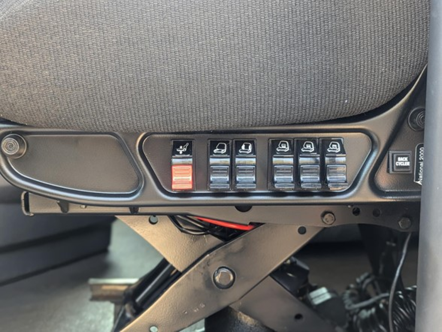 Tractor truck cab interior switch panel with multiple seat heater/power switches and a red emergency switch, part of Freightliner Cascadia 126 dashboard view.