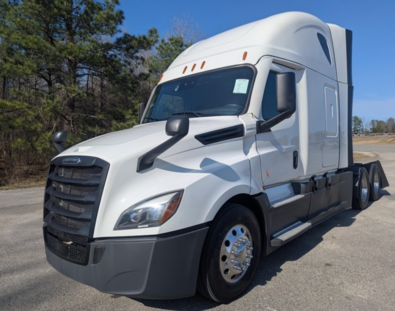 Freightliner Cascadia 126 tractor-trailer in white, front-left view with sleeper cab, chrome wheels, and aerodynamic mirrors.
