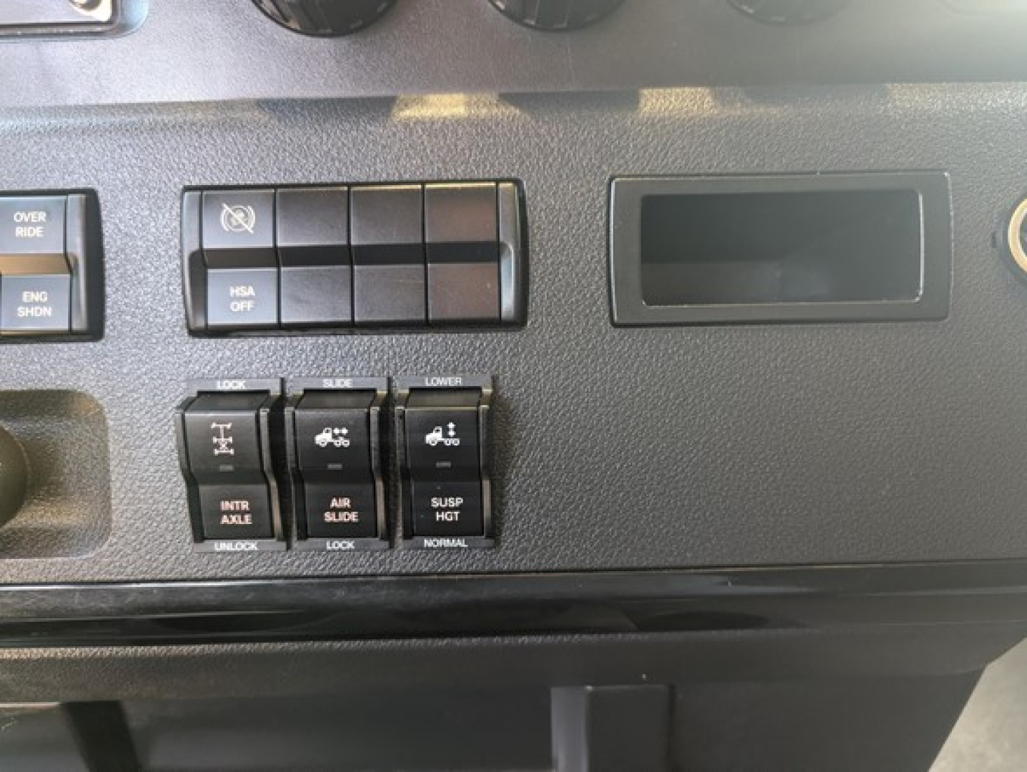 Dashboard switches and controls in Freightliner Cascadia truck cab showing various toggle panels and empty gauge recess.