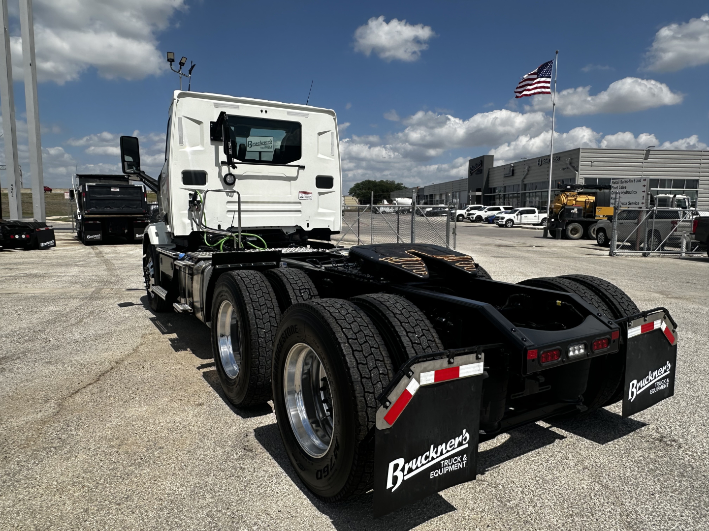 Truck chassis and rear view showing a white cab on a Mack AN64T tractor with dual rear axles, fifth-wheel area, and mudflaps labeled Buckner's Truck Group.