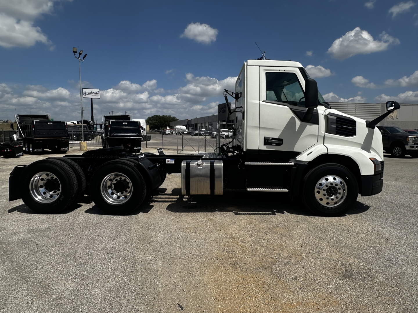 Truck chassis side view showing Mack AN64T cab and dual rear axles in a dealership lot.