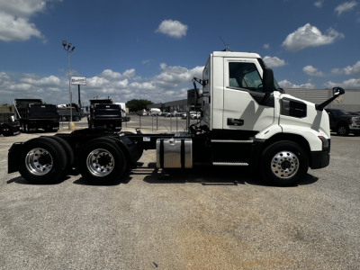 Truck chassis side view showing Mack AN64T cab and dual rear axles in a dealership lot.