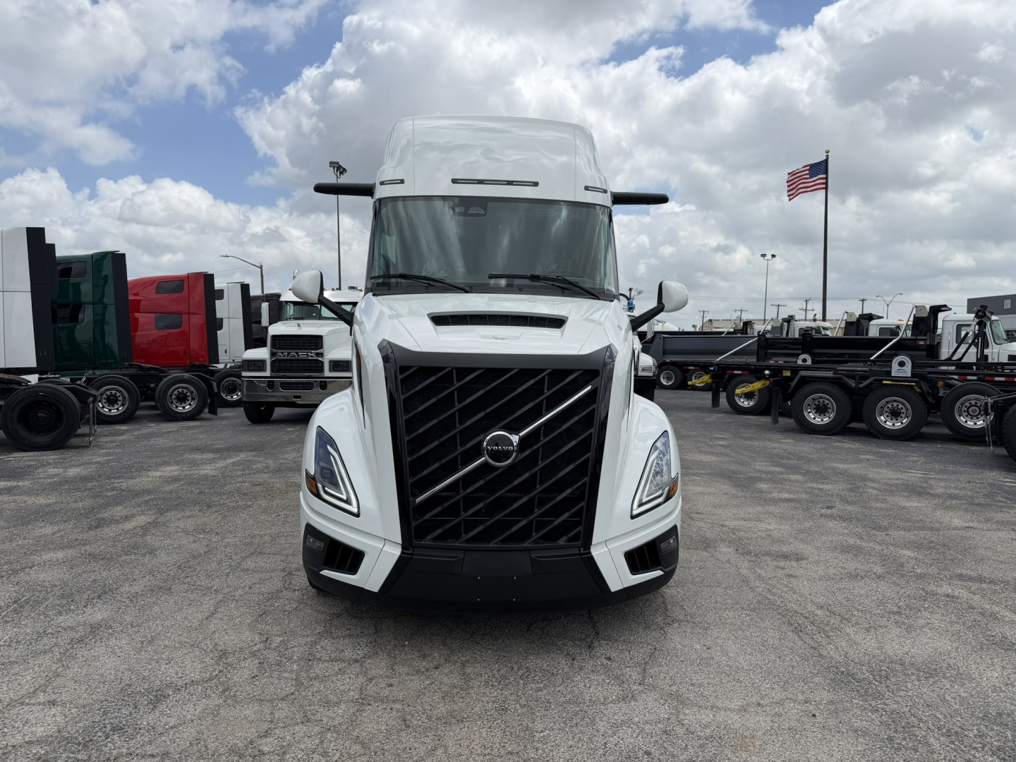Front view of a white Volvo VNL truck in a dealership lot with other trucks in background.
