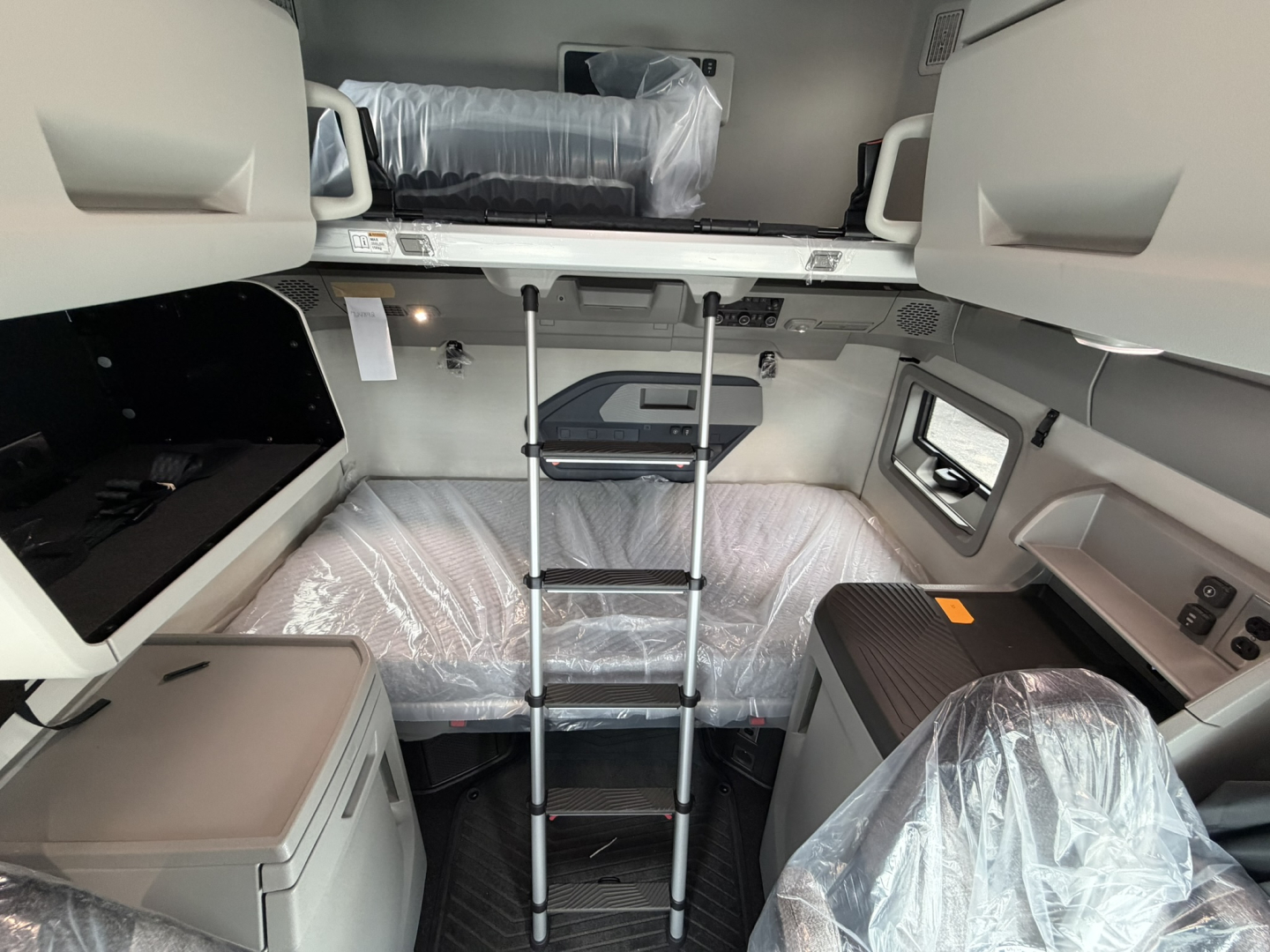 Volvo VNL64T860 truck cab interior showing upper bunk, ladder, and storage compartments in a new sleeper cab.