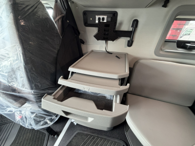 Cab interior of a new Volvo VNL truck showing a mounted fold-out tray system with multiple trays and a monitor bracket on the wall.