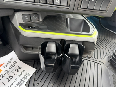 Interior of 2027 Volvo VNL truck cab showing cup holders and center console with neon-green trim and dash controls.
