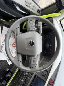 Volvo VNL64T860 interior showing steering wheel with Volvo emblem and control buttons, digital instrument cluster, and bright lime green accents.