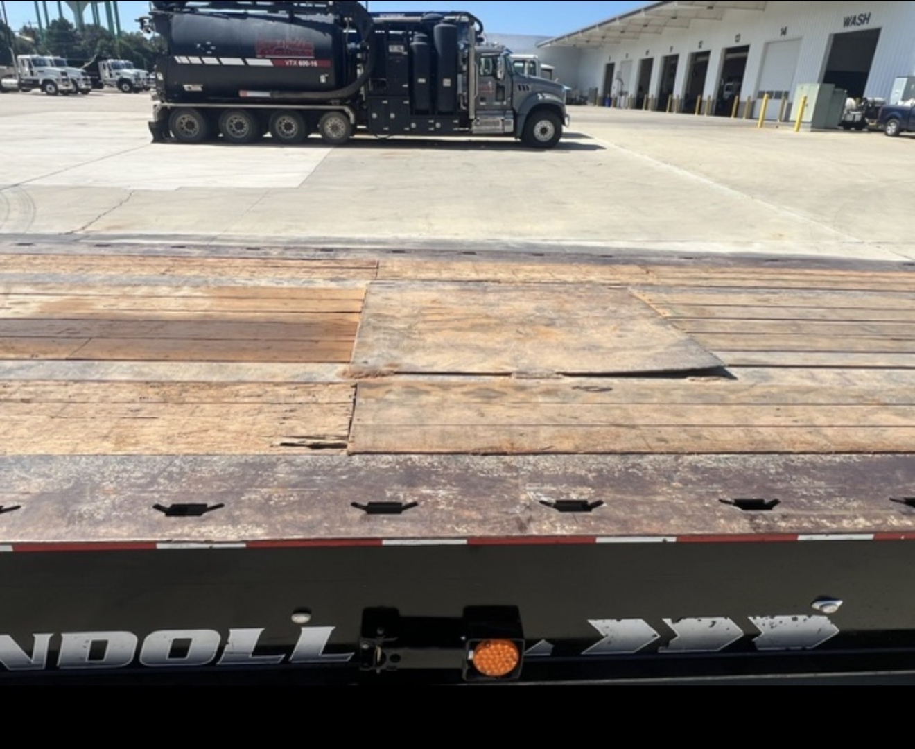 Landoll 455 trailer bed with wooden planks and steel edge shown from rear side, industrial lot in background
