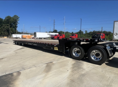 Flatbed trailer showing Landoll 455 trailer with dual tires and long black deck. Visible text includes Landoll branding on side and wheel rims.