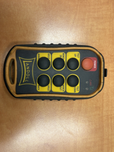 Remote control with yellow panel and black buttons for Landoll trailer system. Buttons labeled: A G E N? Not fully clear. Red power button on right. Brand 'LANDOLL' on left. Overall device appears as a control panel likely for trailer opera