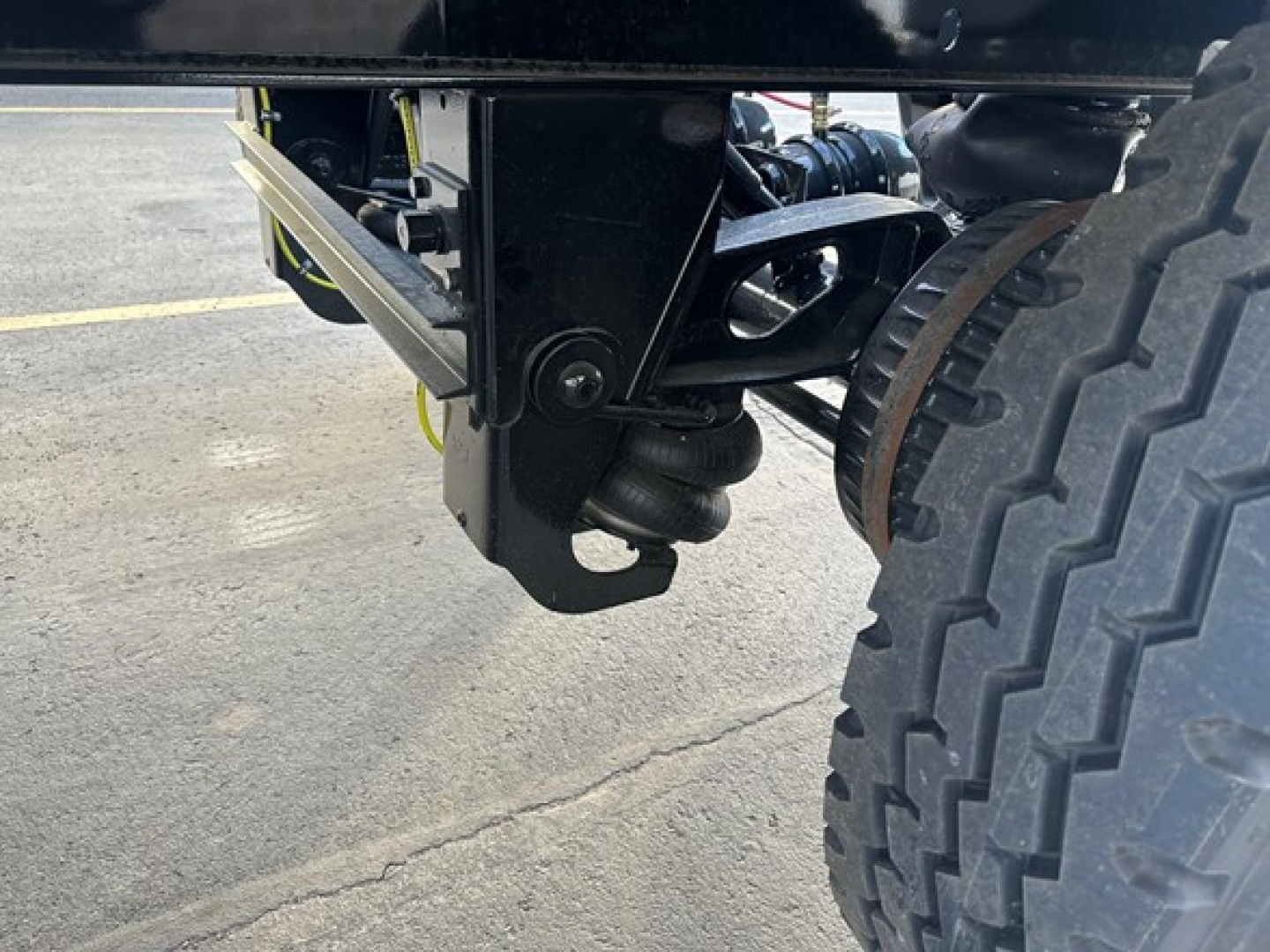 Truck trailer undercarriage showing heavy-duty suspension and dual rear tire with wheel, bracket, and mount visible.