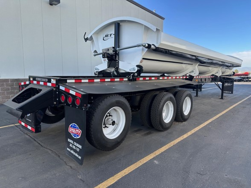 Jet Super Spread trailer showing dump trailer with folded hopper and tandem axles with black mud flaps and reflective tape.
