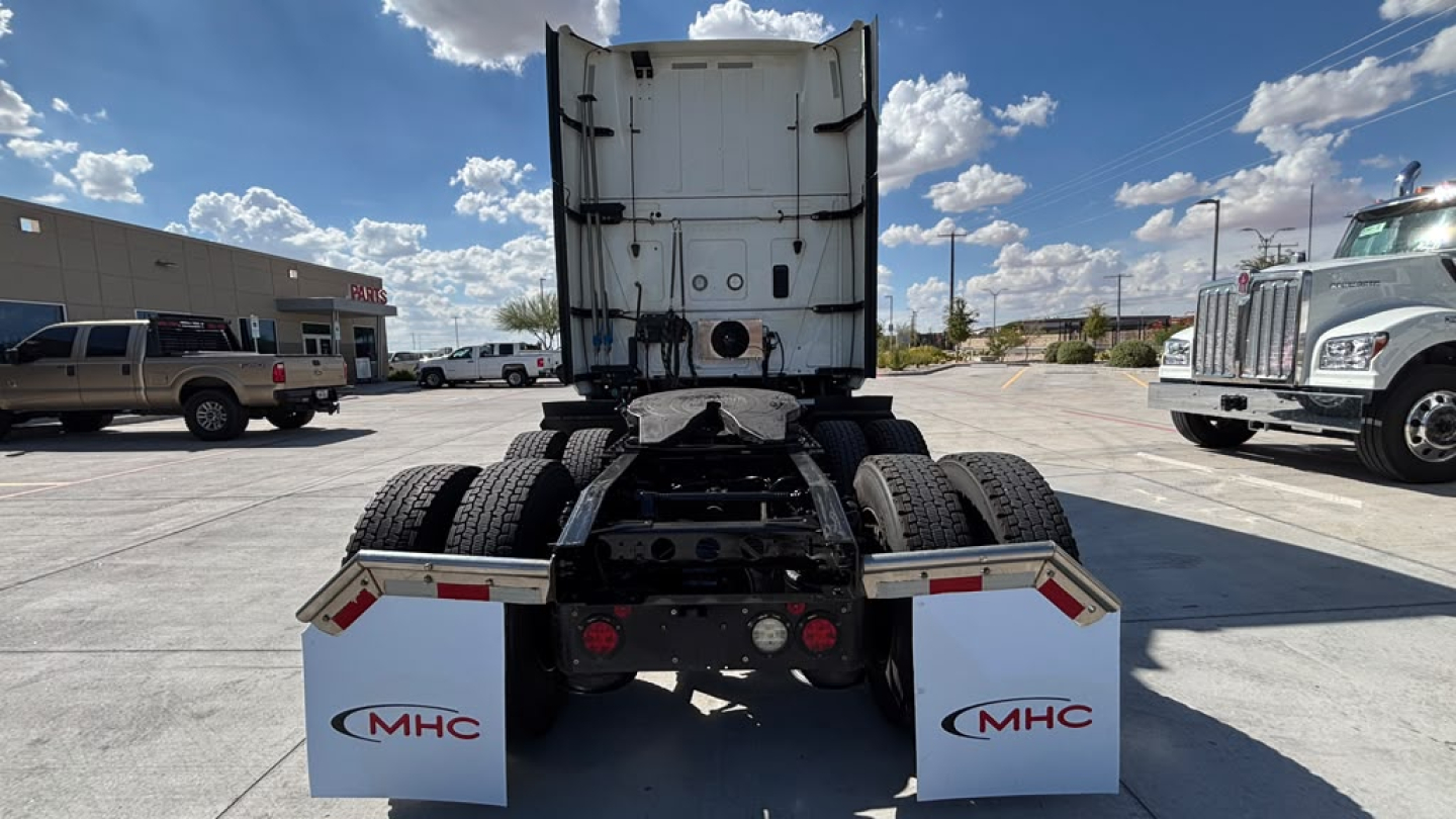 Rear view of a 2022 International LT625 truck tractor showing fifth wheel, dual rear axles, and vertical exhaust area with white trailer behind.