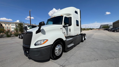 Truck image: 2022 International LT625 conventional sleeper tractor, white cab, side mirrors, black bumper, multiple axles, visible VIN plate area.