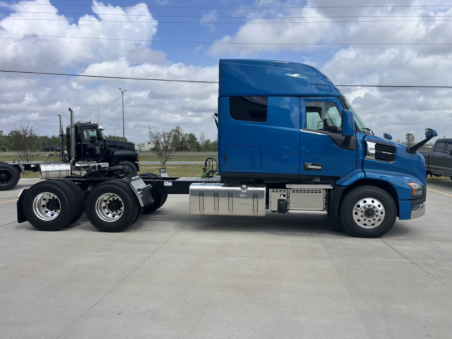 Mack AN64T64 conventional sleeper truck in blue, side view showing cab, dual rear axles, fuel tanks, and chrome steps.