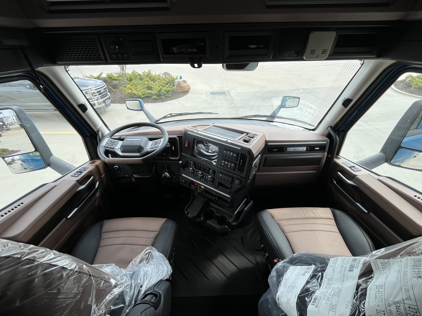 Truck cabin interior of a 2027 Mack AN64T64 conventional sleeper showing the steering wheel, dashboard, and front seats.