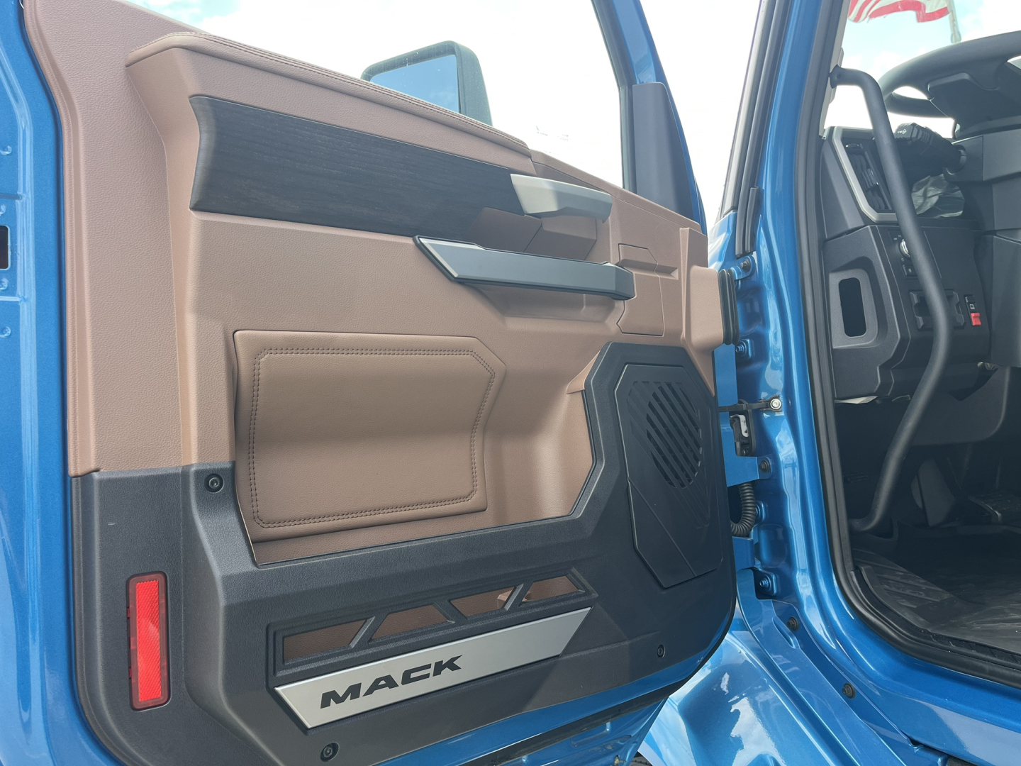 Truck cabin interior door panel with beige and black accents; Mack logo on lower door sill.