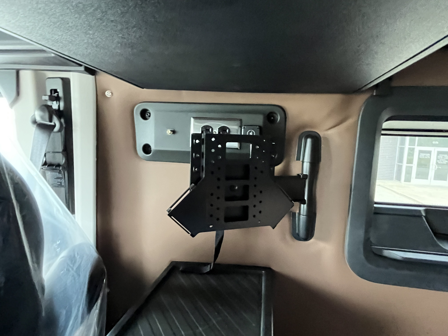 Interior view of a 2027 Mack AN64T64 sleeper cab showing a mounted TV or monitor bracket on a tan wall with window and storage area.