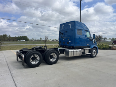 Blue Mack AN64T64 sleeper cab tractor seen from side-rear in parking lot, CHASSIS with dual rear axles, fuel tanks, exhaust stack, and number 7 on cab.