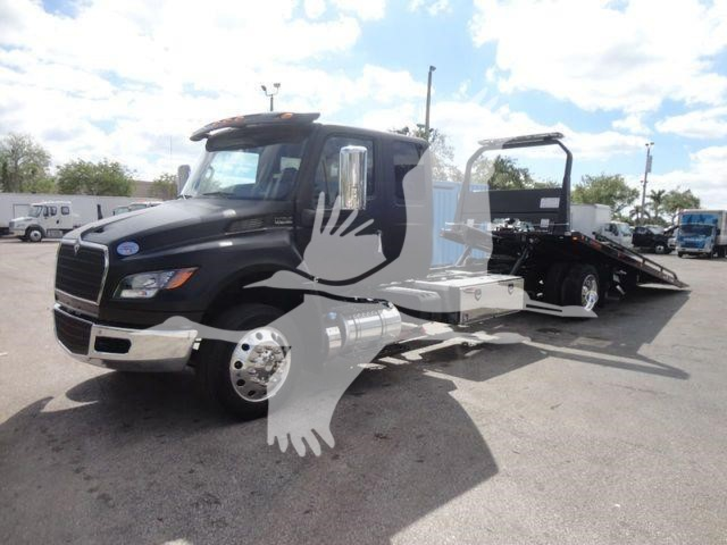 Tow truck with a black cab and flatbed, 'International' style grille; side mirrors; signage and hoses hidden by a watermark; no legible model text visible.
