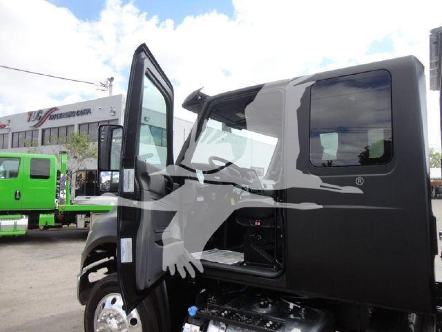 Truck cab with open door showing interior; text on side windows and background signage; black and gray truck body
