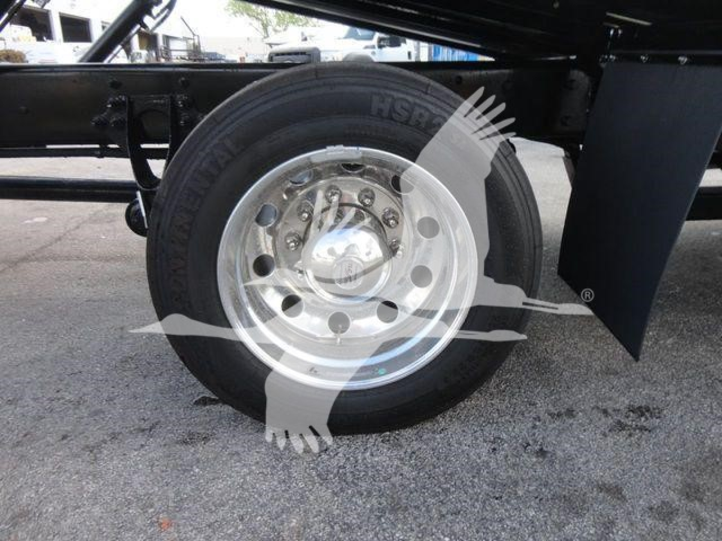 Wheel hub and tire of a truck trailer showing hub cap and lug nuts with discernible text on tire.