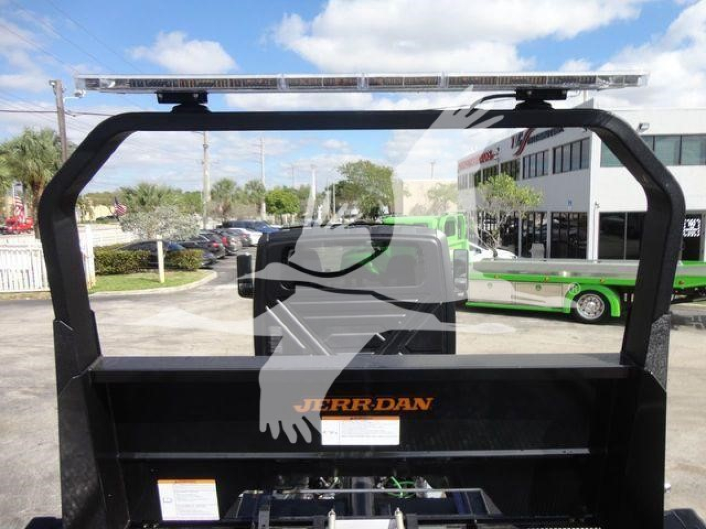 Truck bed of a rollback unit with a Jerr-Dan logo on the toolbox and a raised light bar on top, visible in a dealership lot.