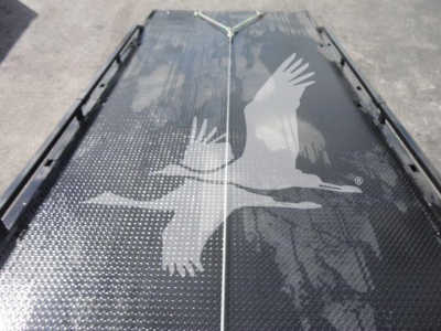 Platform bed of a rollback truck trailer with a diamond plate surface and a white bird graphic.