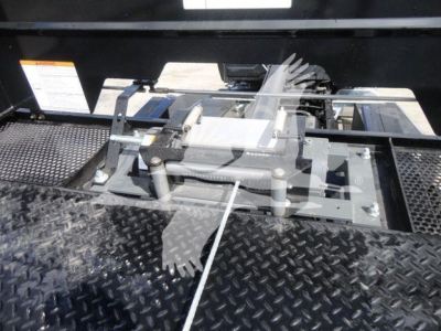 Truck bed area with hydraulic winch and gear mechanism, metal diamond plate surface, cables and levers visible.