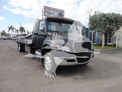 Truck bay showing a 2027 International MV rollback truck front left side view with gray paint and large front grille.