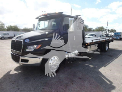 Truck exterior with a flatbed rollback body showing branding stickers and windows; text visible includes vehicle shape but no legible model-specific text.