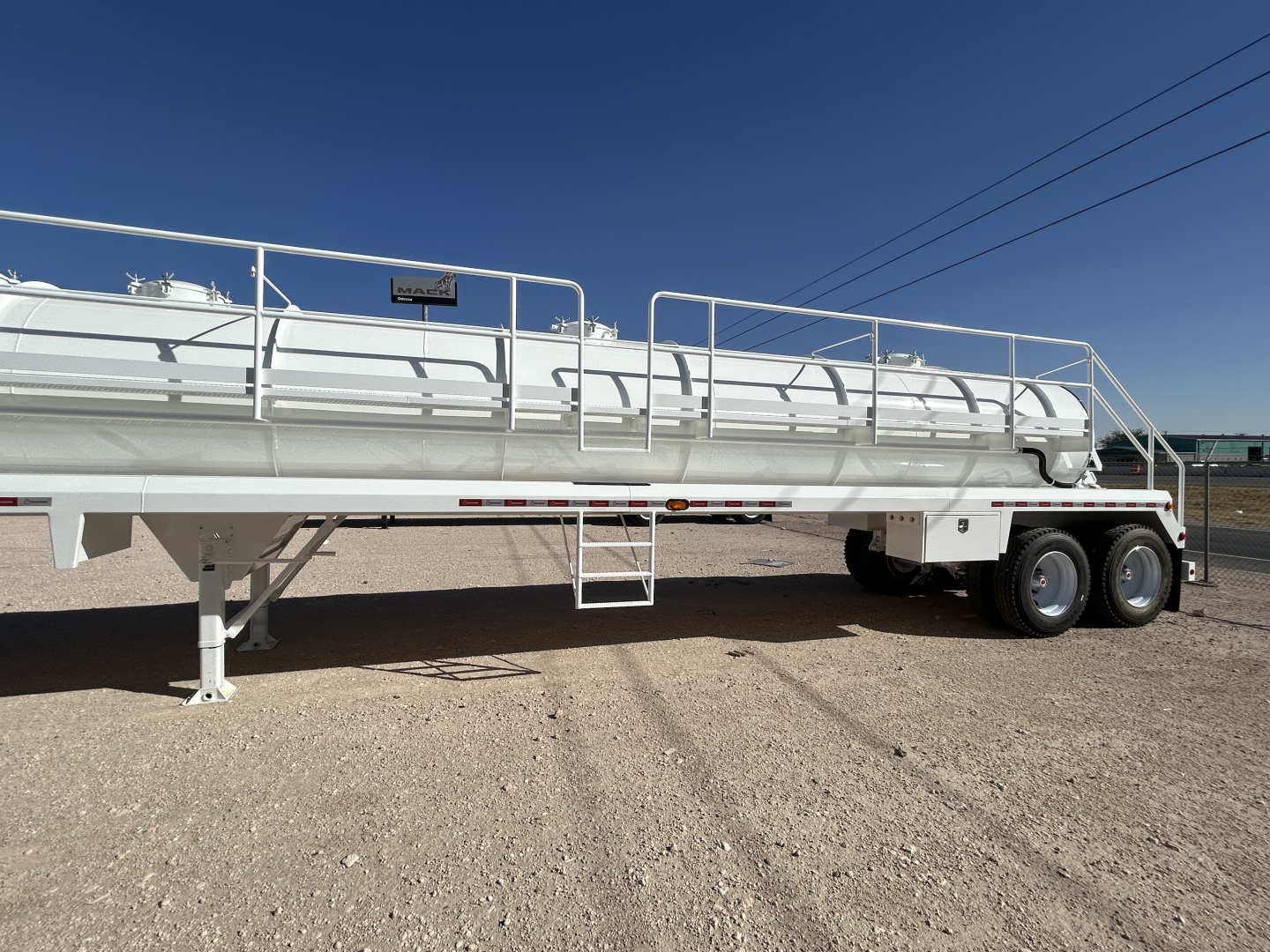 Trailer side view showing white Dragon 130BBL vacuum trailer with ladders, rails, and dual rear axles.