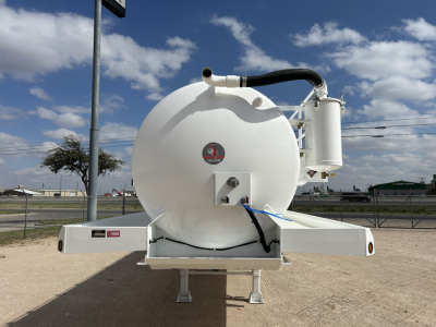 Rear view of a white Dragon 130BBL vacuum trailer showing a circular tank, black hoses, and a mounted filtration/air unit on the right side.