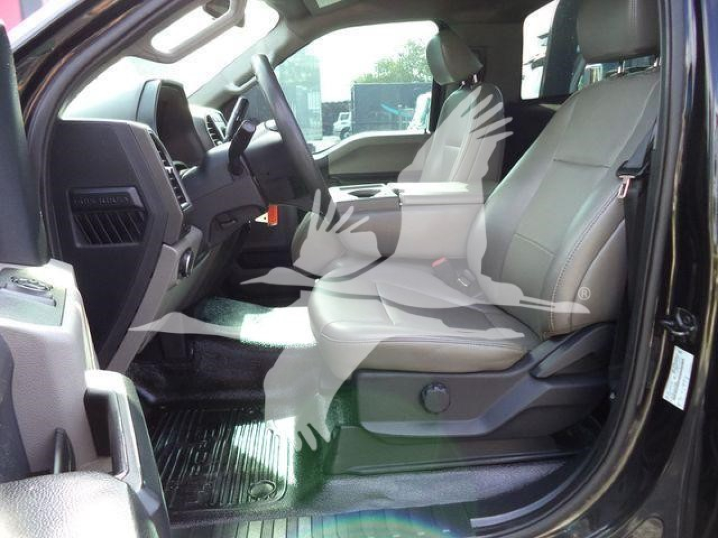 Interior of a 2022 Ford F600 truck showing front seats and dashboard from the driver's side with light gray upholstery and rubber floor mats.