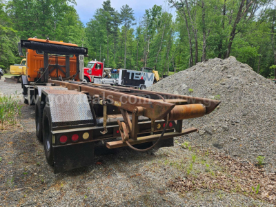 Autocar roll-off truck rear with rust-colored frame showing hitch and storage platform.