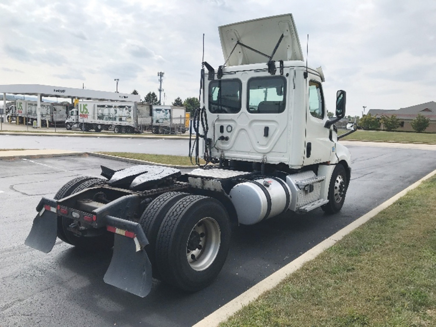 Freightliner Cascadia126 tractor rear and cab shown with raised hood; side view reveals fuel tanks, dual rear axles, and mud flaps.