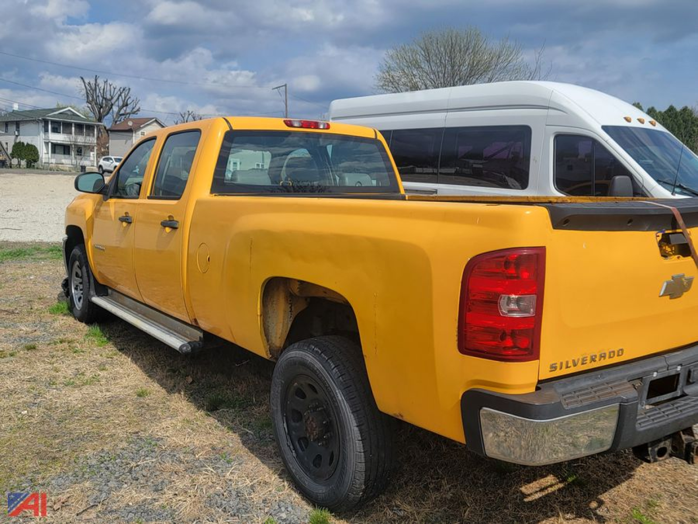 Chevrolet Silverado 3500HD Crew Cab pickup truck in yellow parked next to a white camper shell, visible rear and side view.
