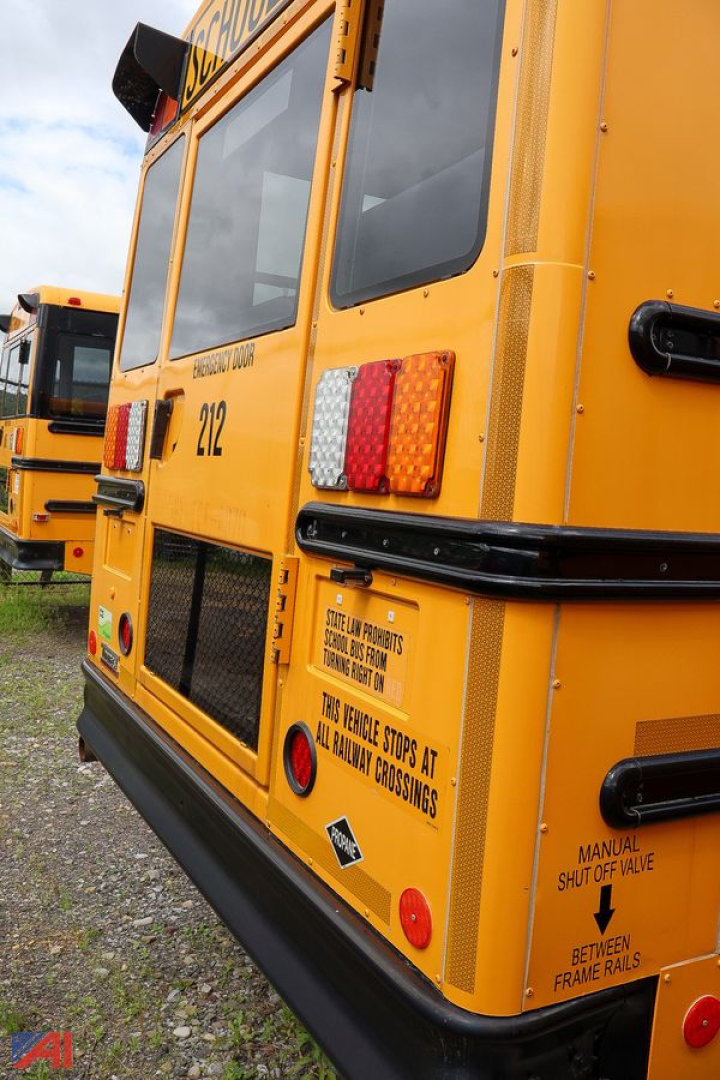 Rear of a yellow Freightliner school bus showing tail lights, bus number 212, and safety signage on the back panel.