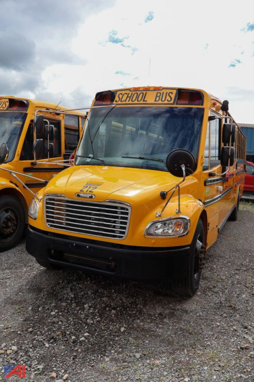 School bus front view showing bright yellow Freightliner C2 Saf-T-Liner with 'SCHOOL BUS' sign above windshield and round black mirrors.